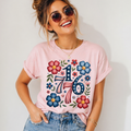 Woman wearing a pink patriotic, independence day t-shirt with floral 1776, standing against a plain background