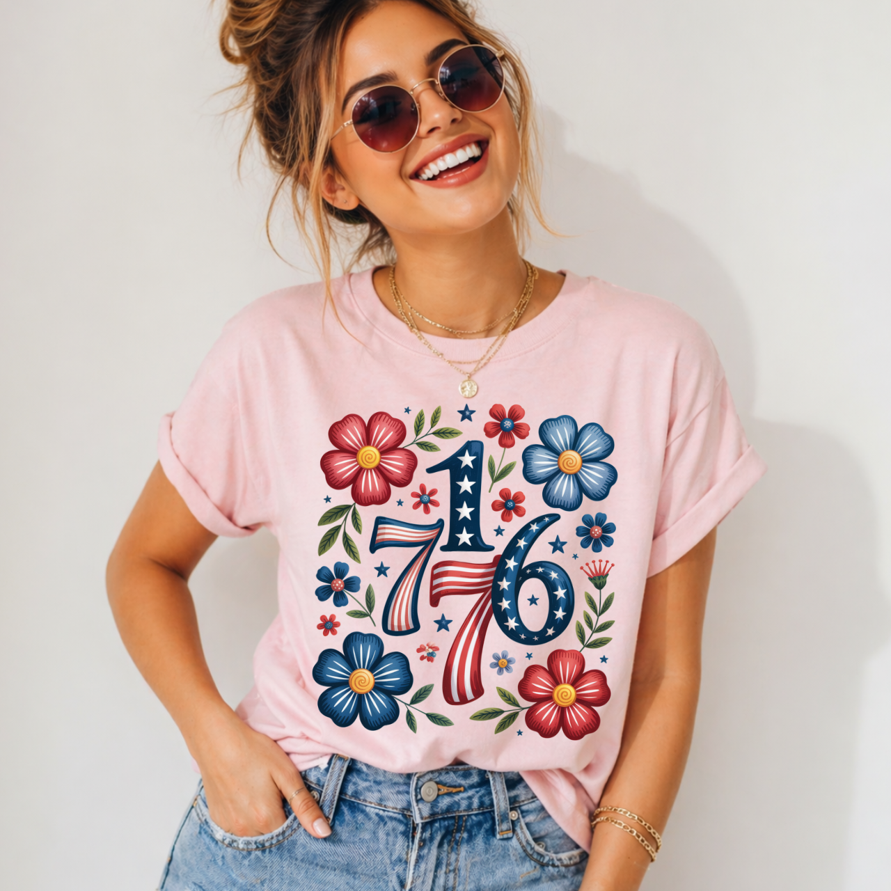 Woman wearing a pink patriotic, independence day t-shirt with floral 1776, standing against a plain background