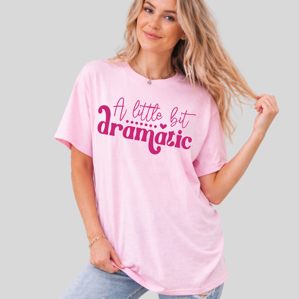 Woman wearing a pink t-shirt with 'A little bit dramatic' text on a plain background