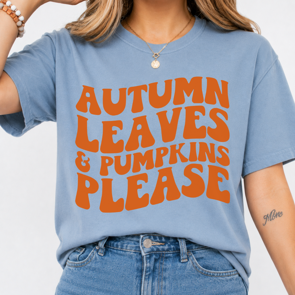 Woman wearing a stone blue Autumn Leaves and Pumpkins Please fall graphic tee with bold orange retro lettering.
