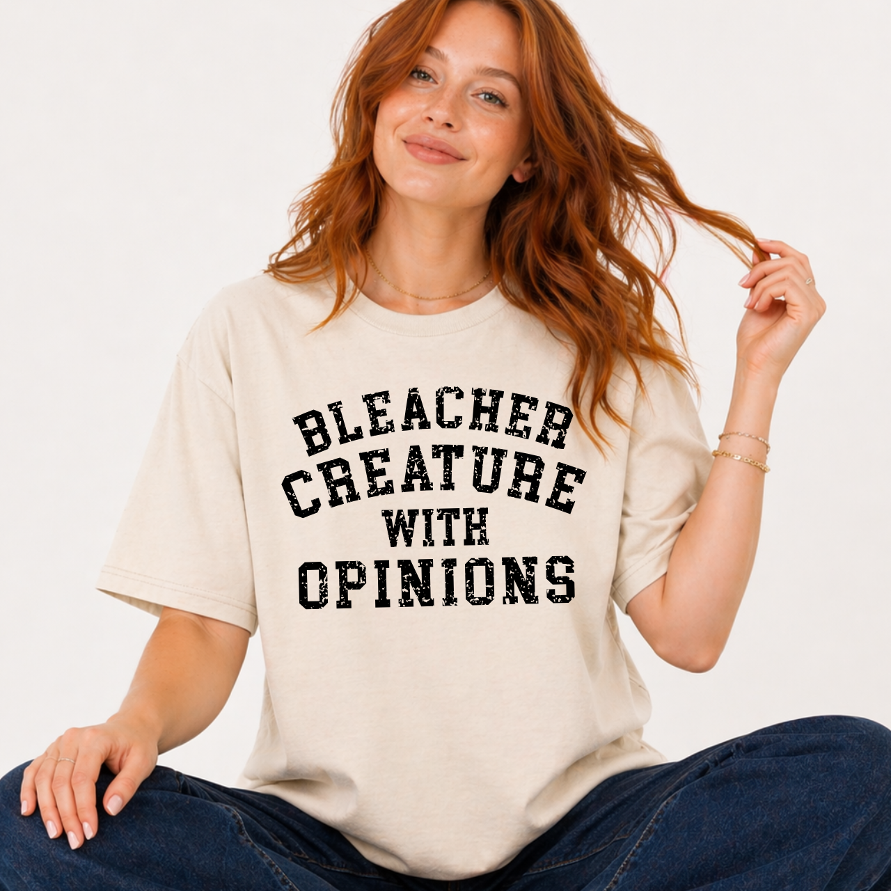 Woman wearing a beige t-shirt with 'BLEACHER CREATURE WITH OPINIONS' text.