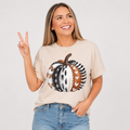 Woman wearing a cream sand colored patterned pumpkin fall graphic tee with a neutral boho pumpkin design
