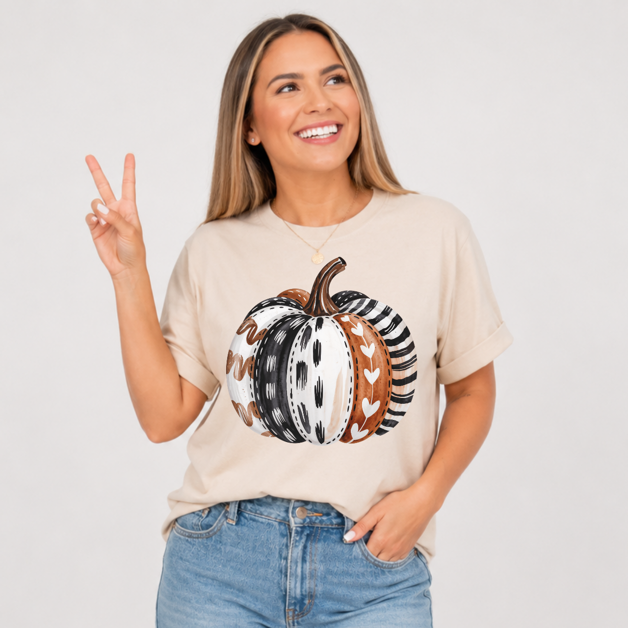 Woman wearing a cream sand colored patterned pumpkin fall graphic tee with a neutral boho pumpkin design