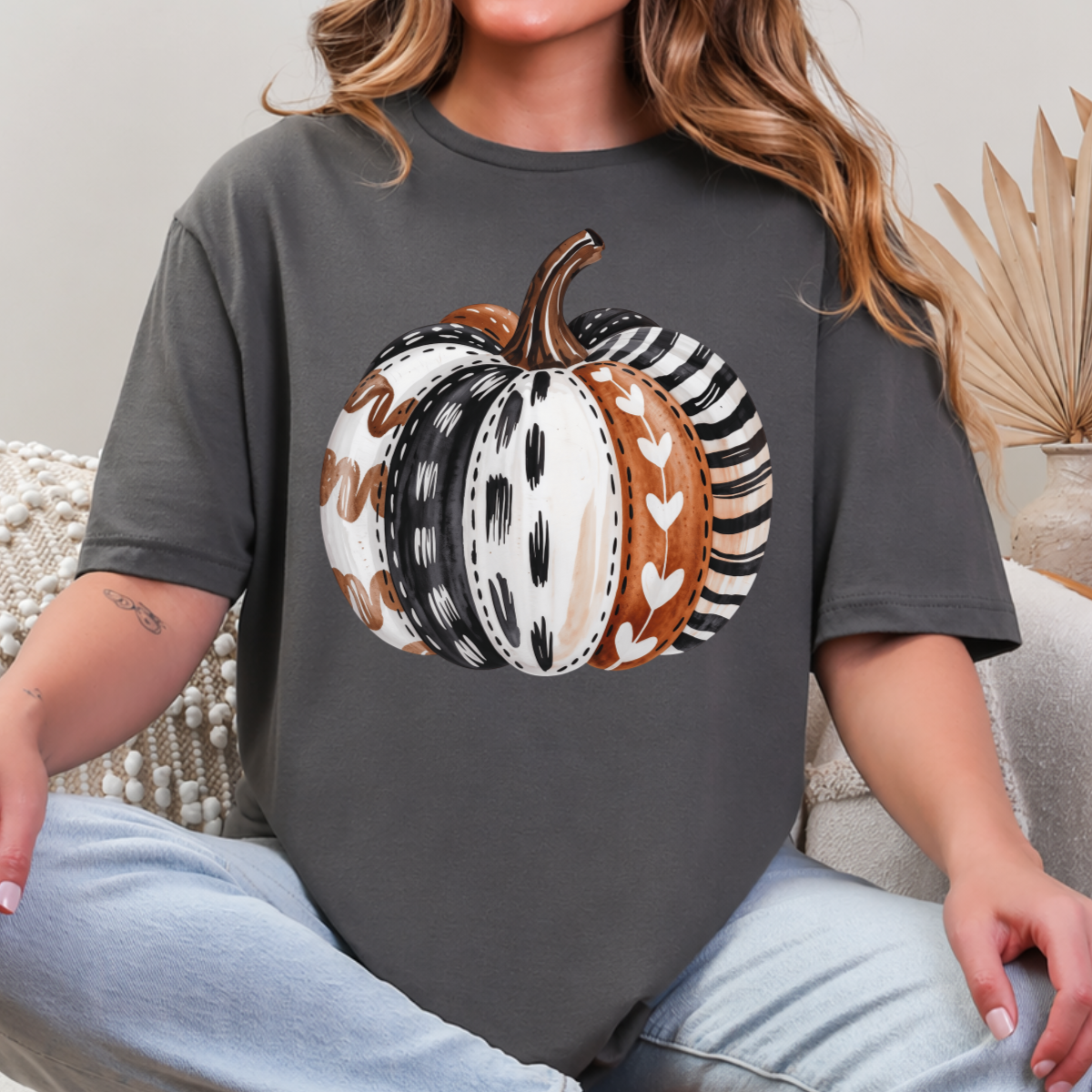 Woman wearing a charcoal patterned pumpkin fall graphic tee with a neutral boho pumpkin design.