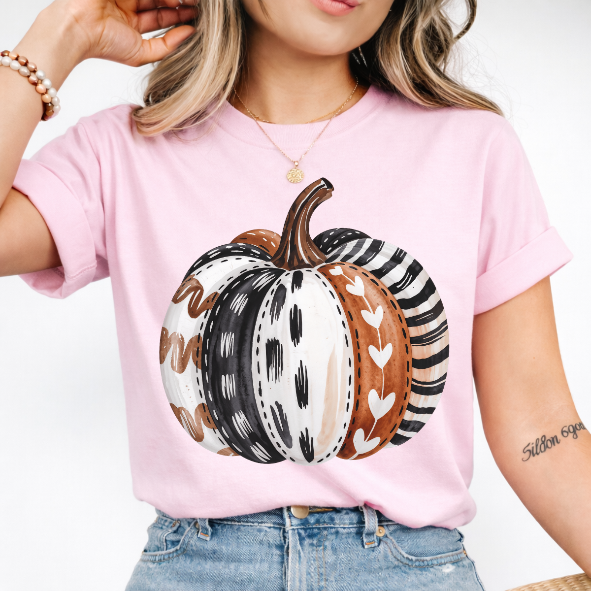 Woman wearing a light pink patterned pumpkin fall graphic tee with a neutral boho pumpkin design.