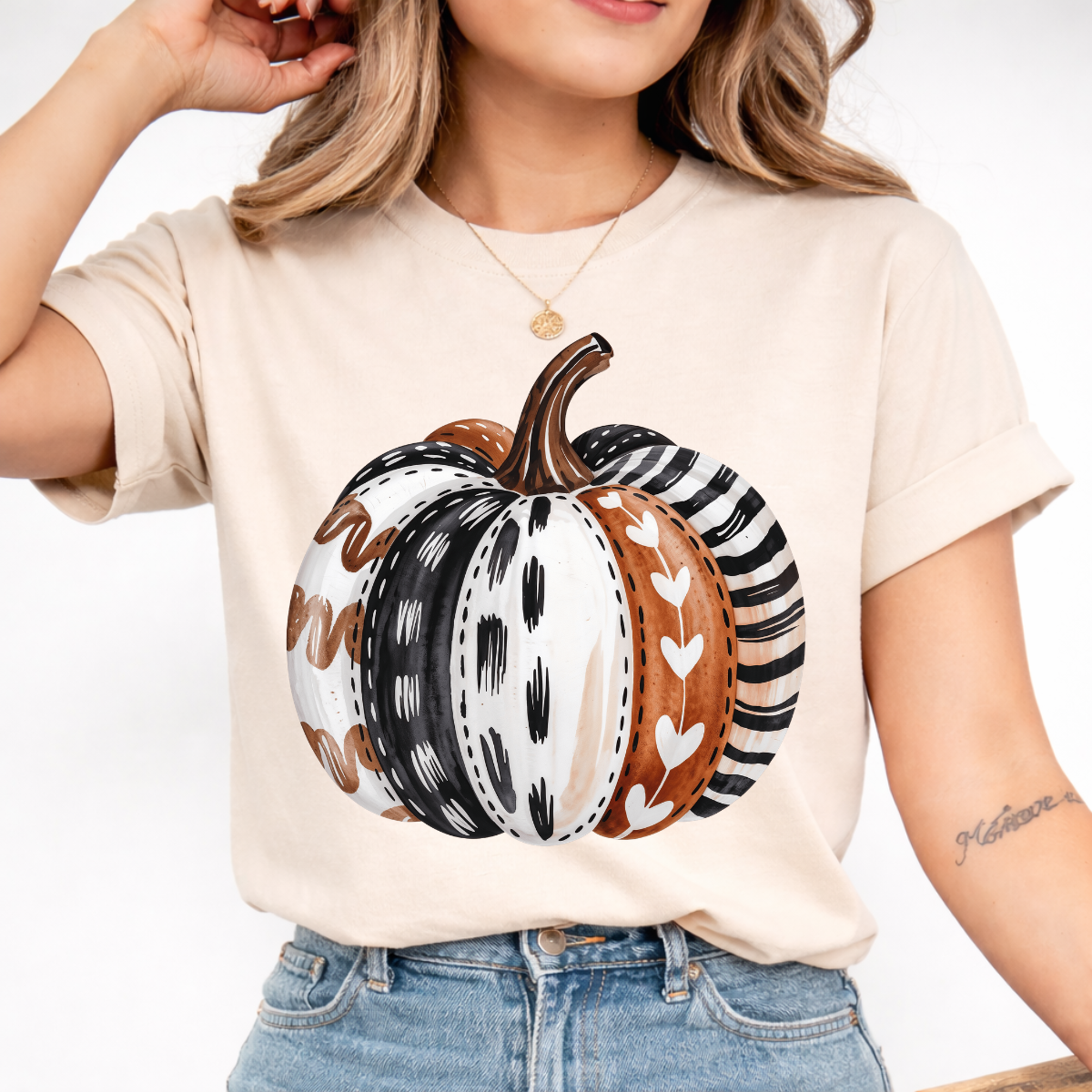 Woman wearing a sand colored patterned pumpkin fall graphic tee with a neutral boho pumpkin design
