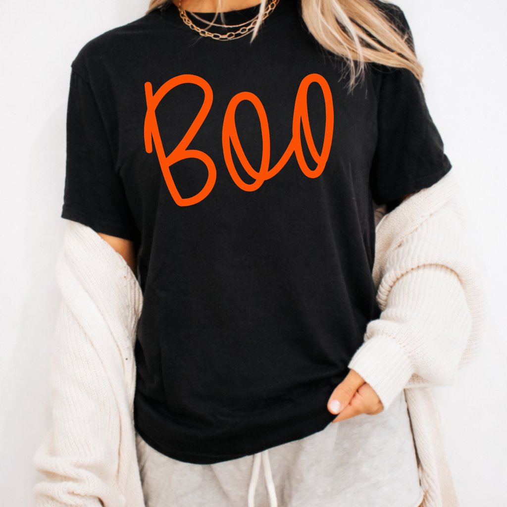 Woman wearing a black Boo Halloween graphic tee with oversized orange script lettering.
