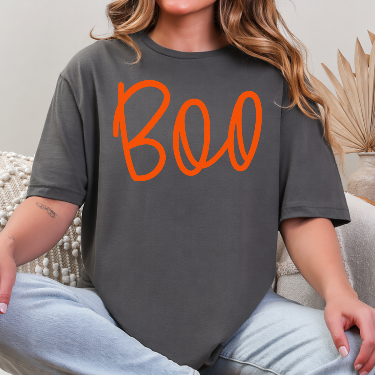 Woman wearing a charcoal Boo Halloween graphic tee with oversized orange script lettering.