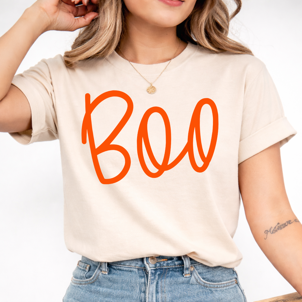 Woman wearing a sand Boo Halloween graphic tee with oversized orange script lettering.