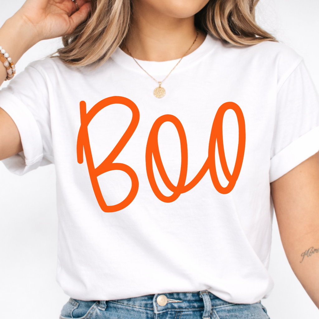 Woman wearing a white Boo Halloween graphic tee with oversized orange script lettering.