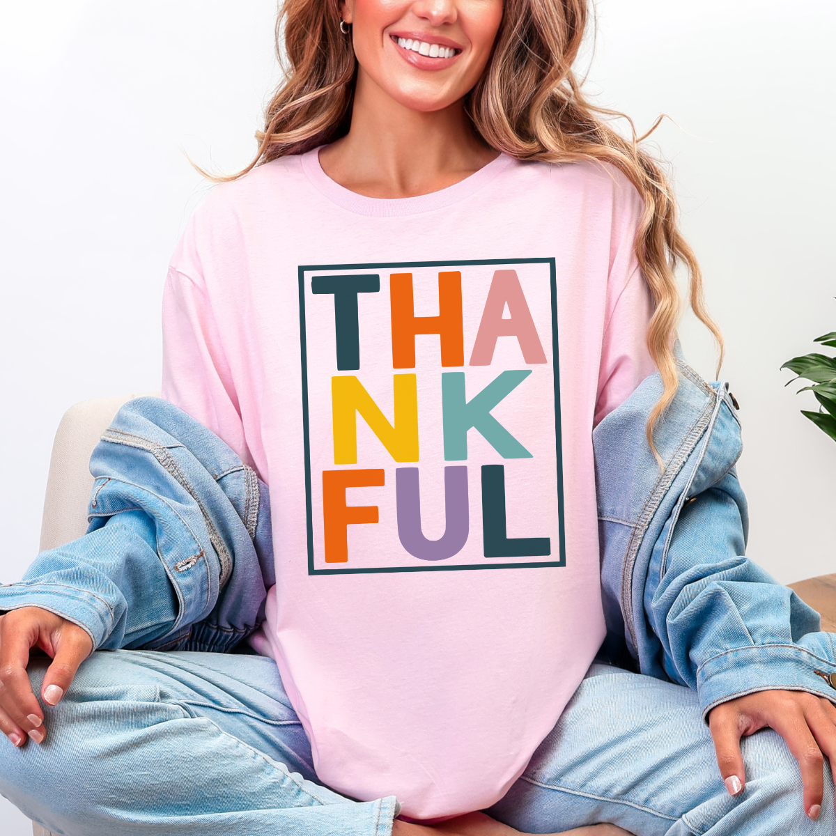 Woman wearing a light pink Thankful Thanksgiving graphic tee with colorful block lettering.