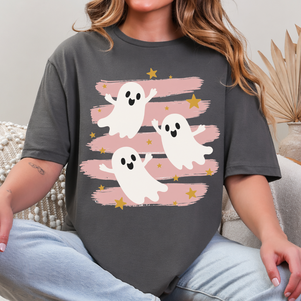 Woman wearing a charcoal Halloween graphic tee with three white ghosts, pink brushstrokes, and gold stars.