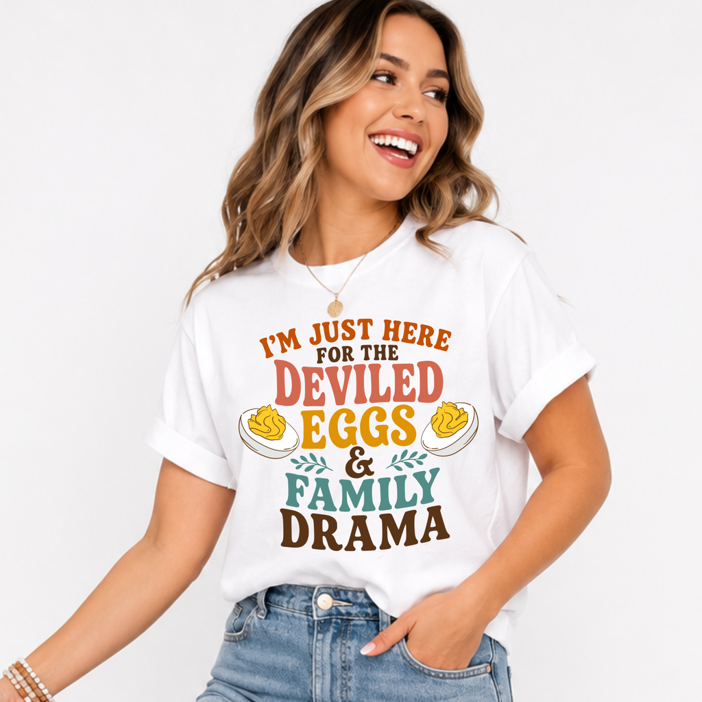 Woman wearing a white Deviled Eggs and Family Drama Thanksgiving graphic tee with colorful lettering and deviled egg illustrations.