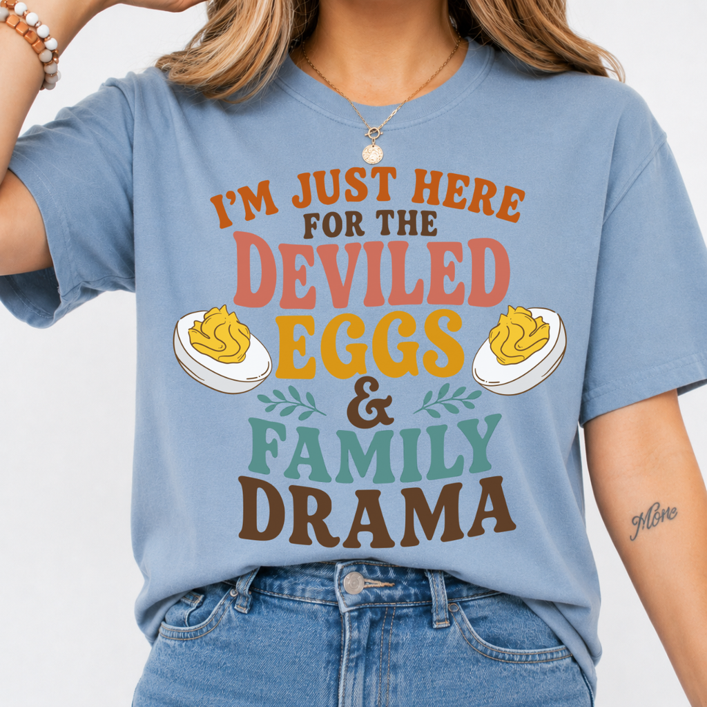 Woman wearing a stone blue Deviled Eggs and Family Drama Thanksgiving graphic tee with colorful lettering and deviled egg illustrations.