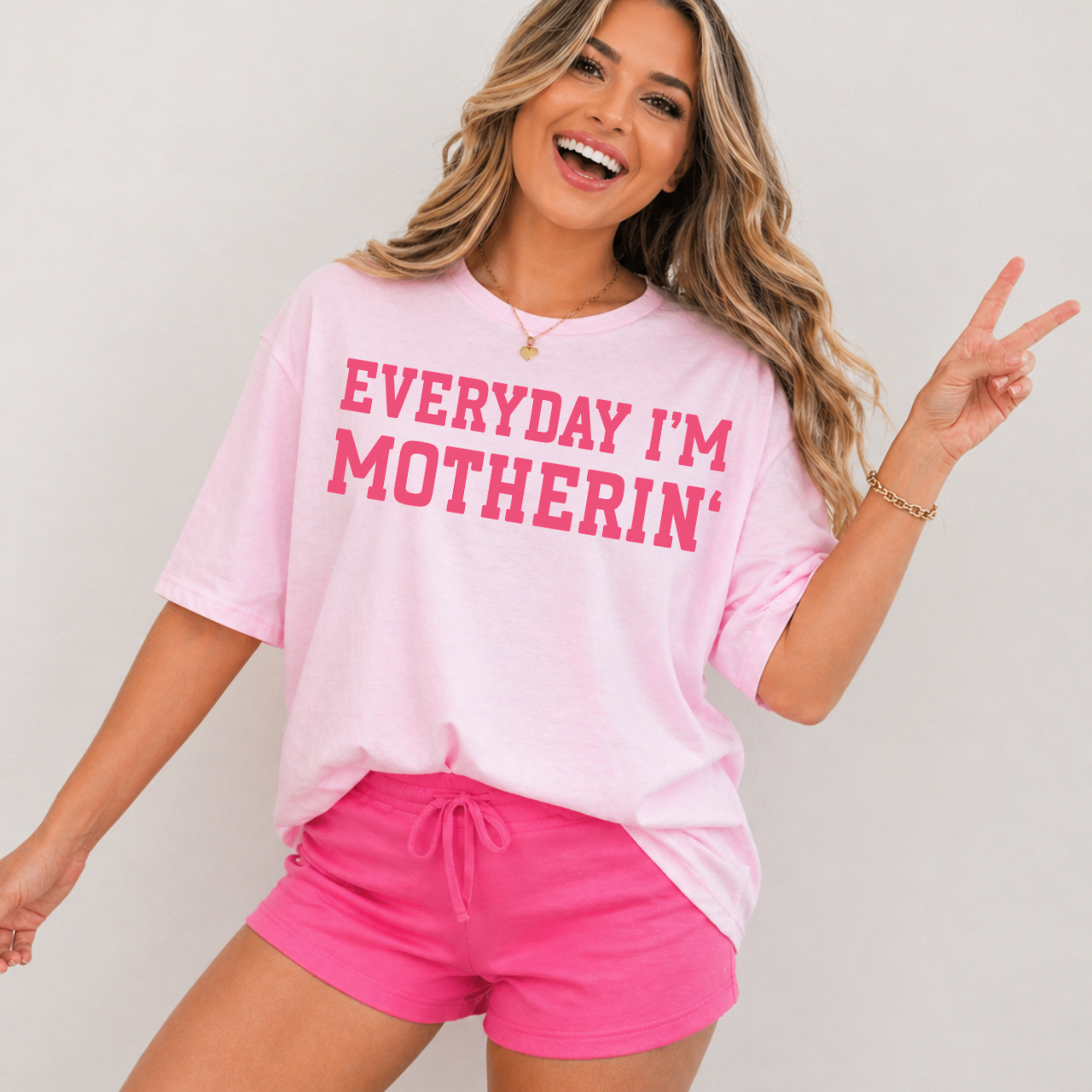 Women in a light pink shirt that says 'Everyday I'm Motherin' in hot pink.
