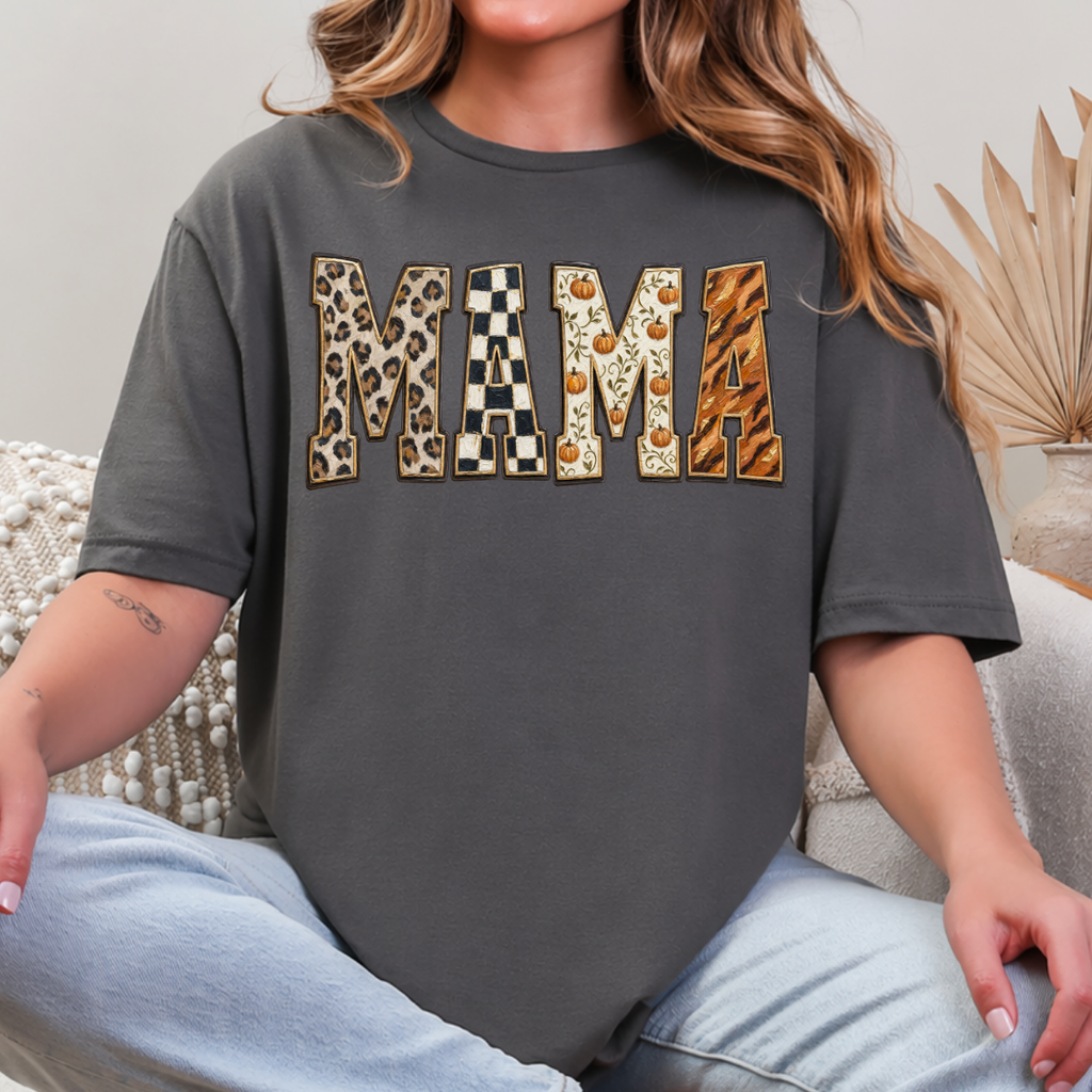 Woman wearing a charcoal Fall Mama graphic tee with leopard print, checkerboard, pumpkin, and orange patterned lettering.