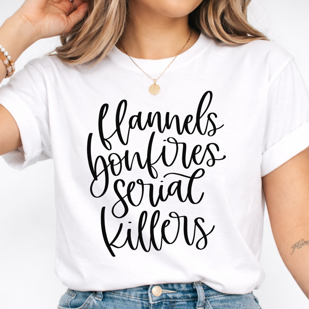 Woman wearing a white Flannels Bonfires and Serial Killers fall graphic tee with black script lettering.