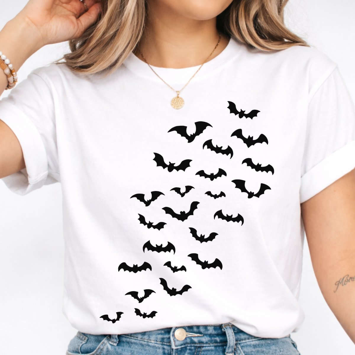 Woman wearing a light pink Halloween graphic tee with cascading black bats across the front.
