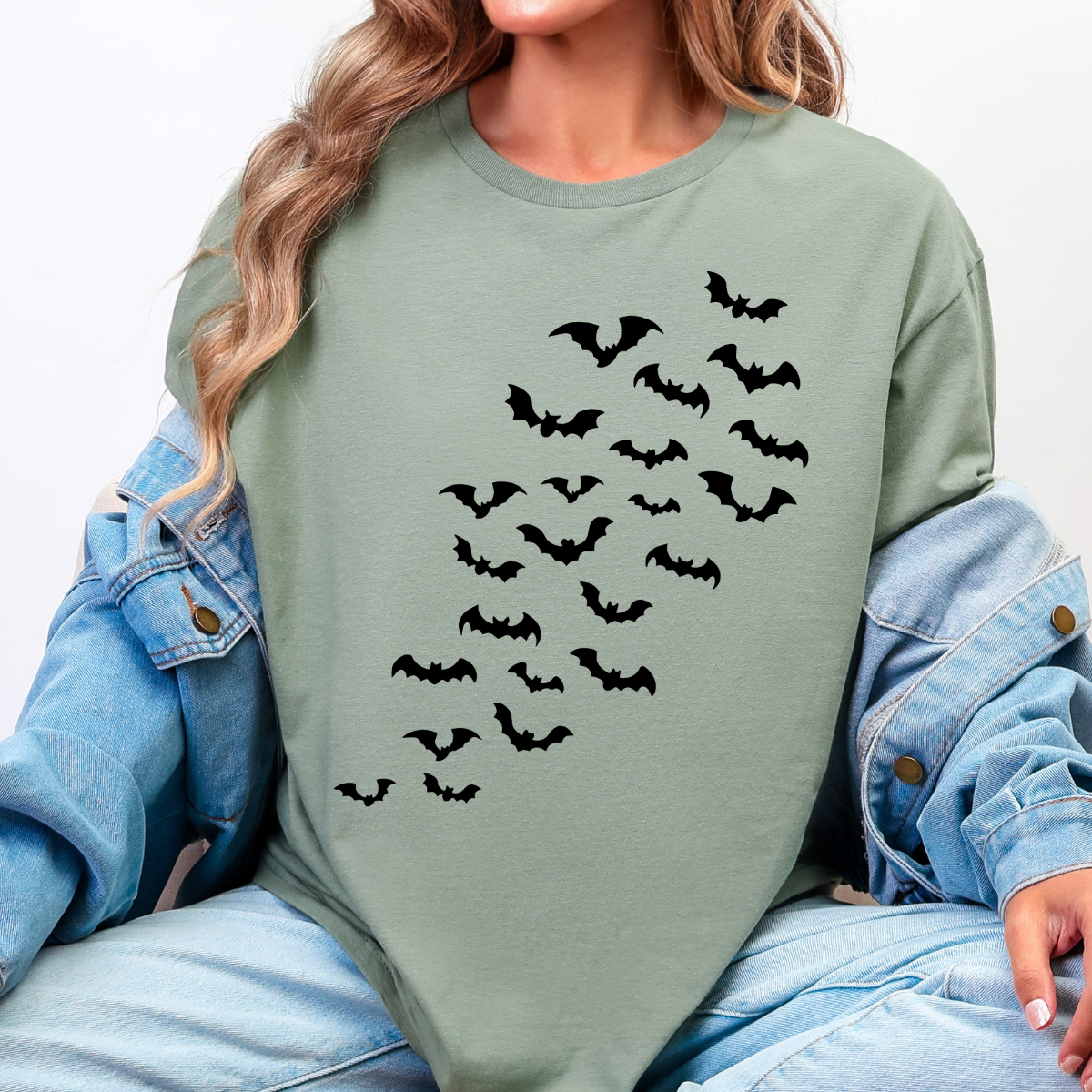 Woman wearing a sage Halloween graphic tee with cascading black bats across the front.