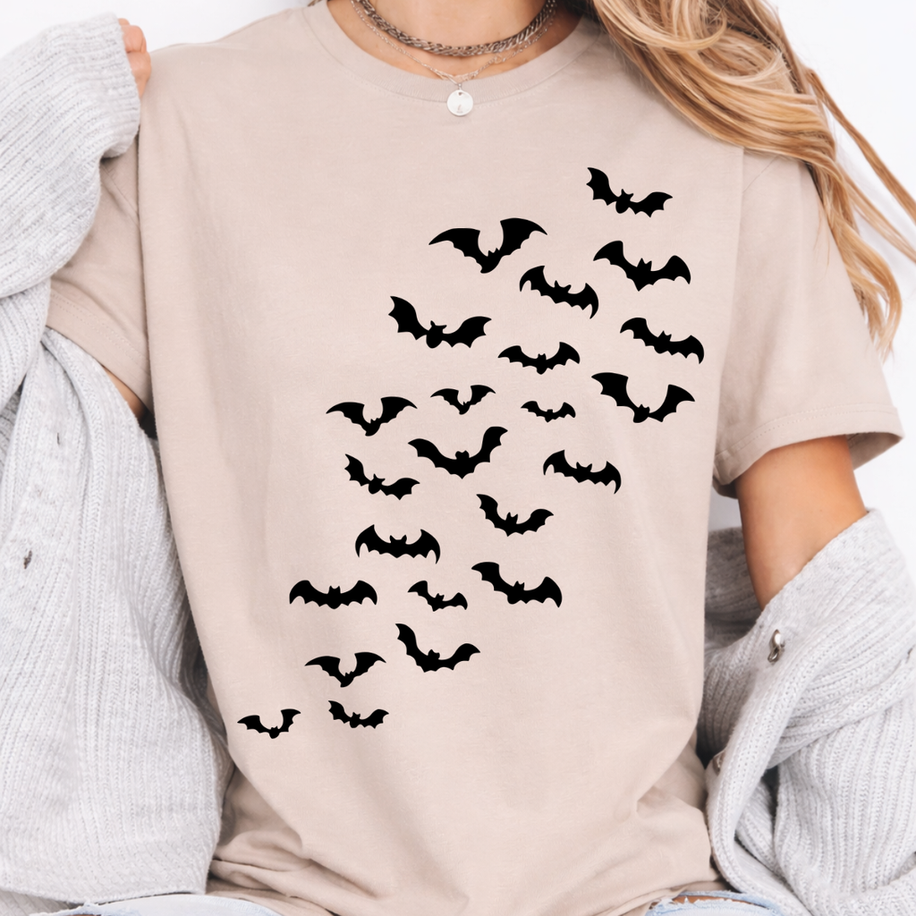 Woman wearing a sand Halloween graphic tee with cascading black bats across the front.