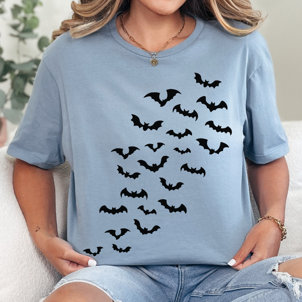 Woman wearing a stone blue Halloween graphic tee with cascading black bats across the front.