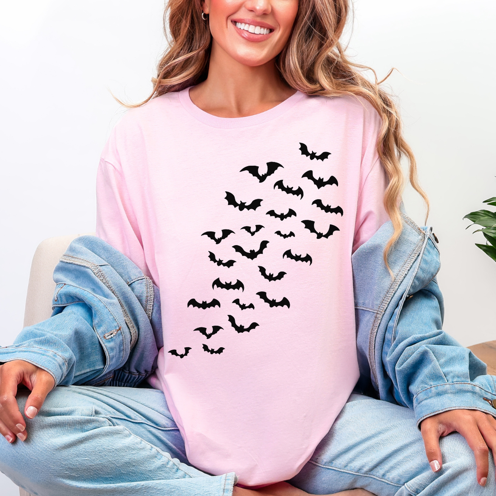 Woman wearing a light pink Halloween graphic tee with cascading black bats across the front.