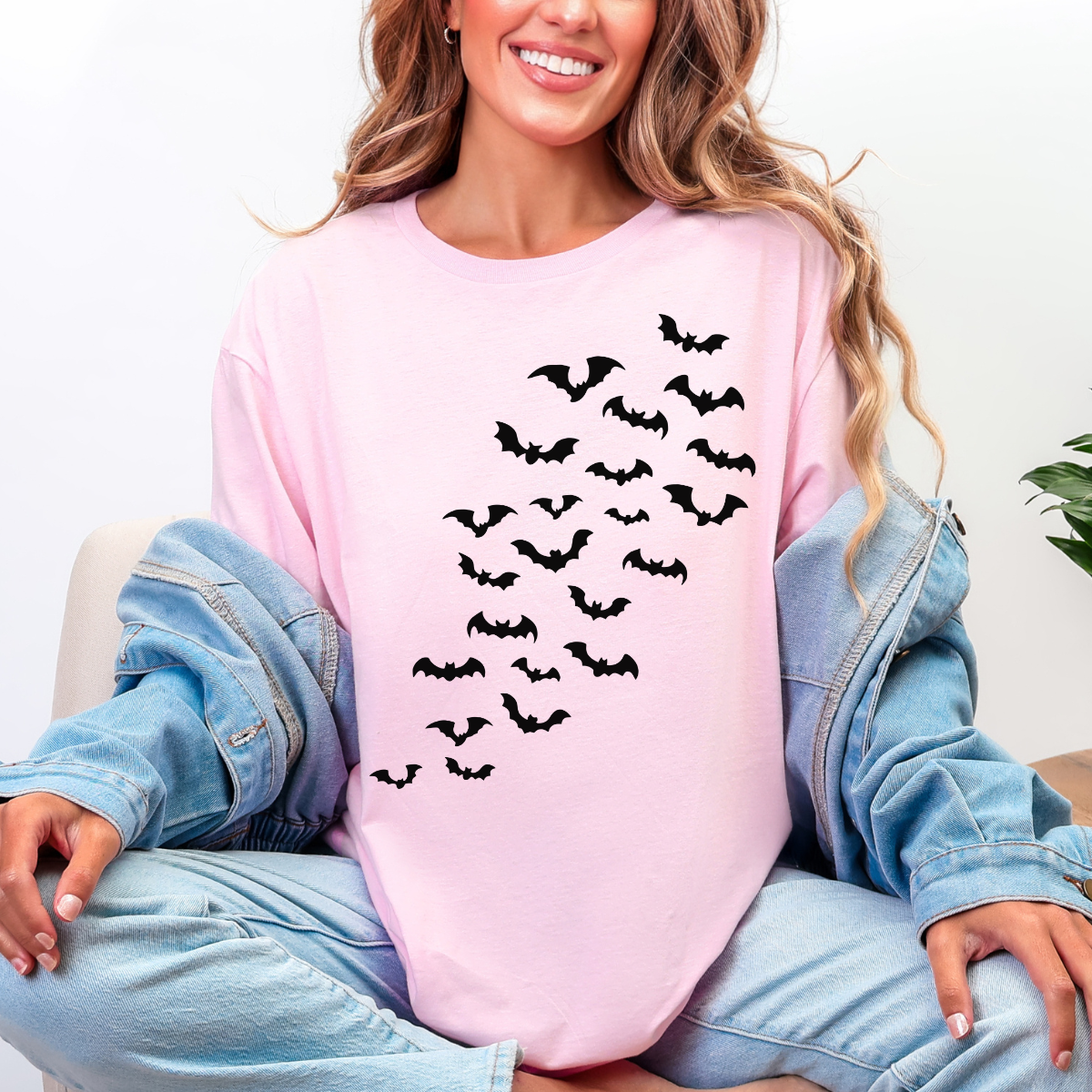 Woman wearing a light pink Halloween graphic tee with cascading black bats across the front.