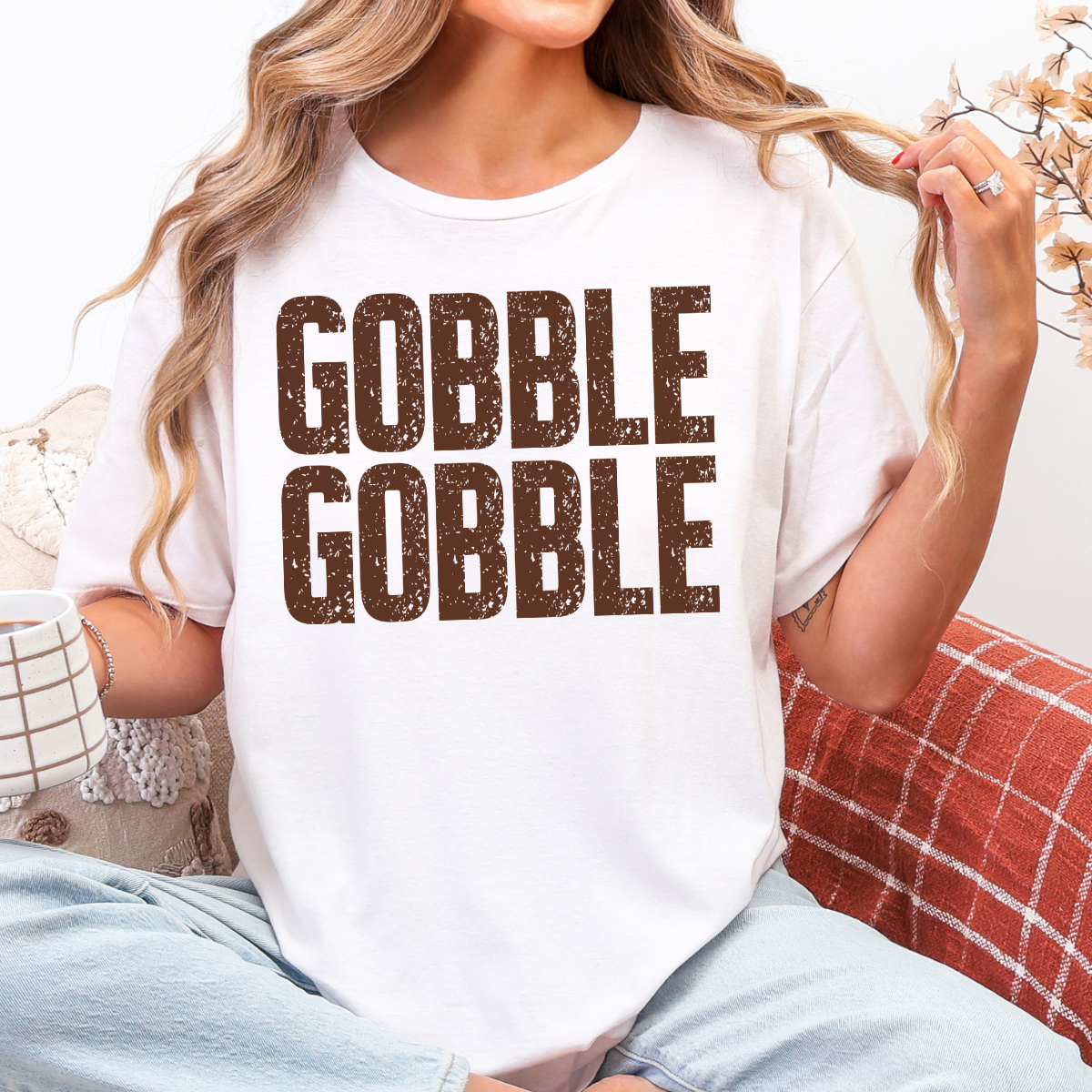 Woman wearing a white Gobble Gobble Thanksgiving graphic tee with distressed brown lettering.
