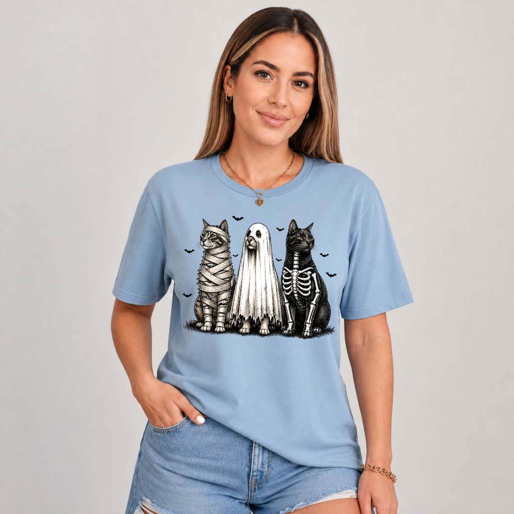 Woman wearing a sage green Halloween cats graphic tee with mummy, ghost, and skeleton cats