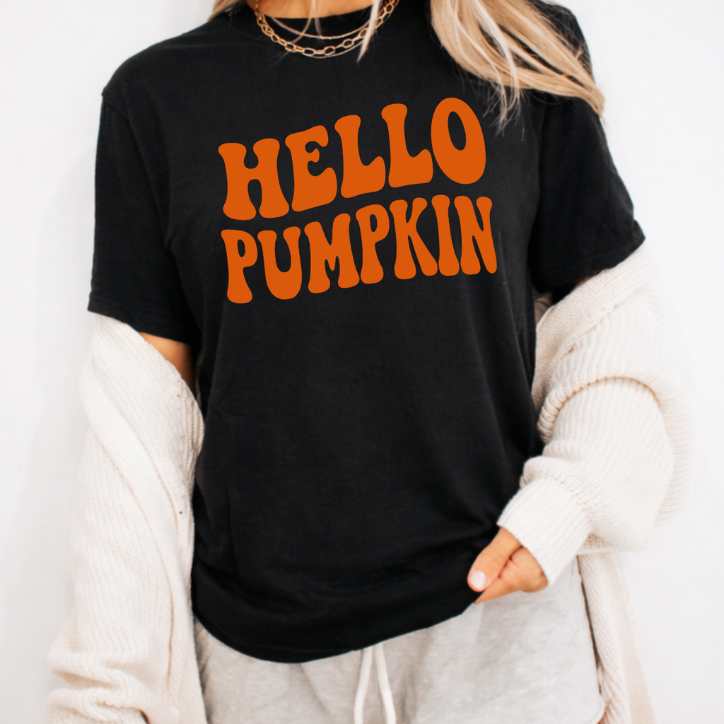 Woman wearing a black Hello Pumpkin fall graphic tee with bold orange retro lettering.