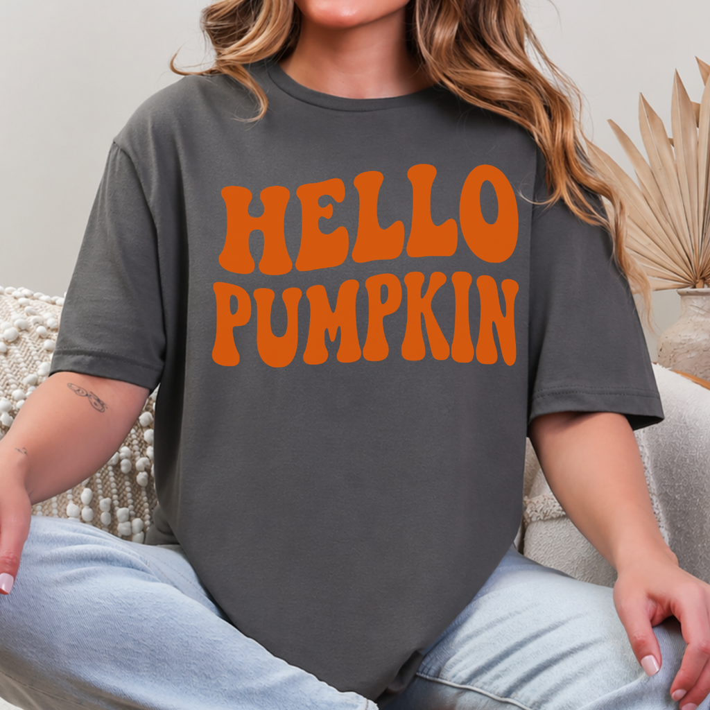 Woman wearing a charcoal Hello Pumpkin fall graphic tee with bold orange retro lettering.
