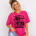 Woman wearing a pink t-shirt with a skeleton graphic and text that says "I Asked Myself If I'm Okay and We Both Started Laughing.