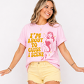 Woman wearing a pink t-shirt with graphic design that says I'm About to Cause a Scene.
