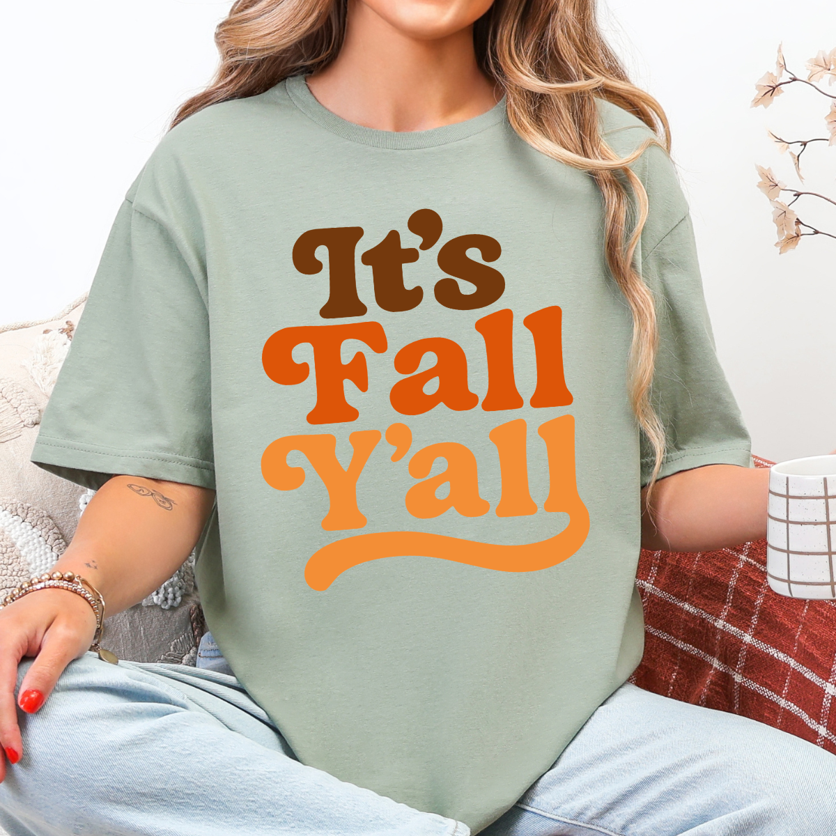 Woman wearing a white It’s Fall Y’all graphic tee with brown and orange retro lettering.