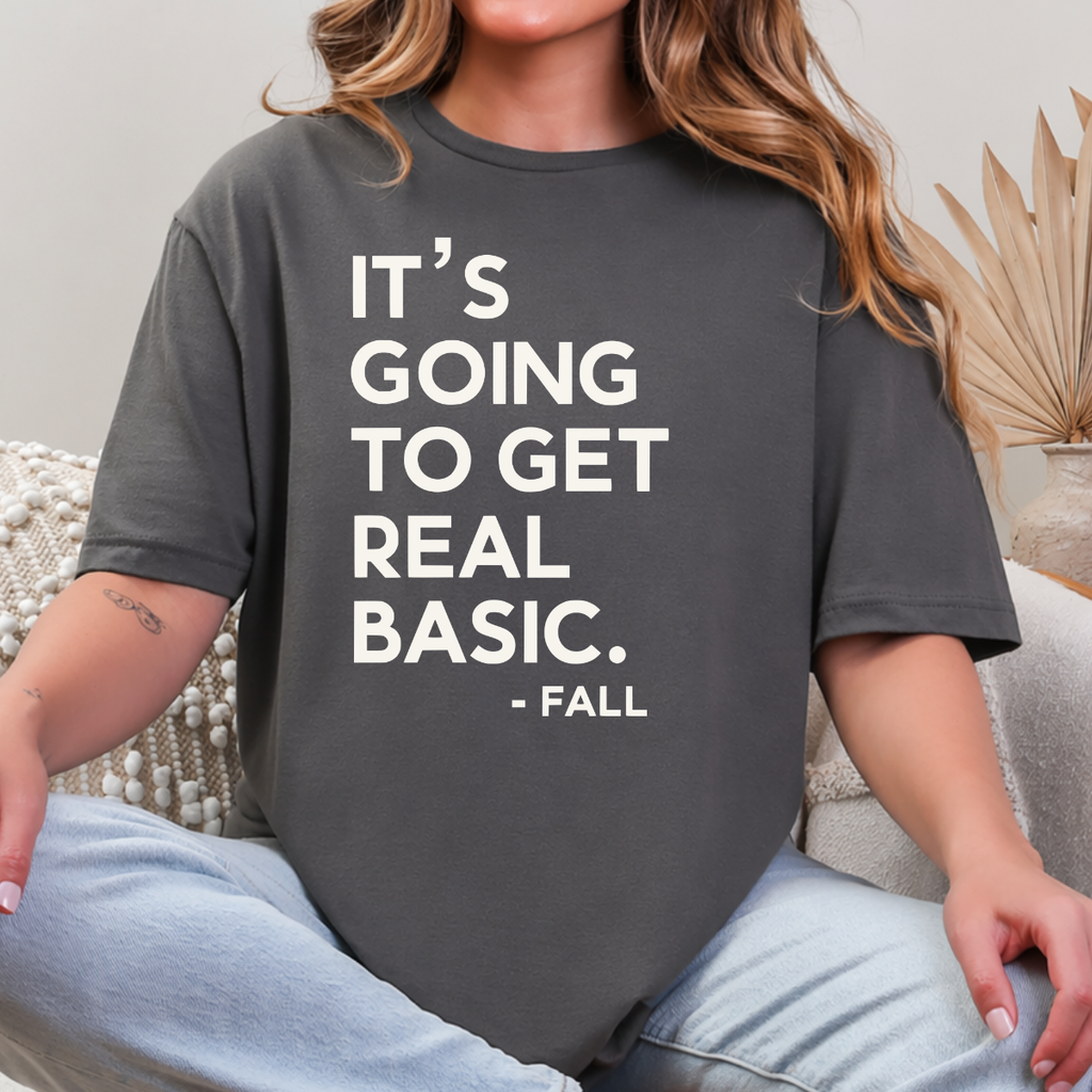 Woman wearing a charcoal It’s Going to Get Real Basic fall graphic tee with bold brown lettering.