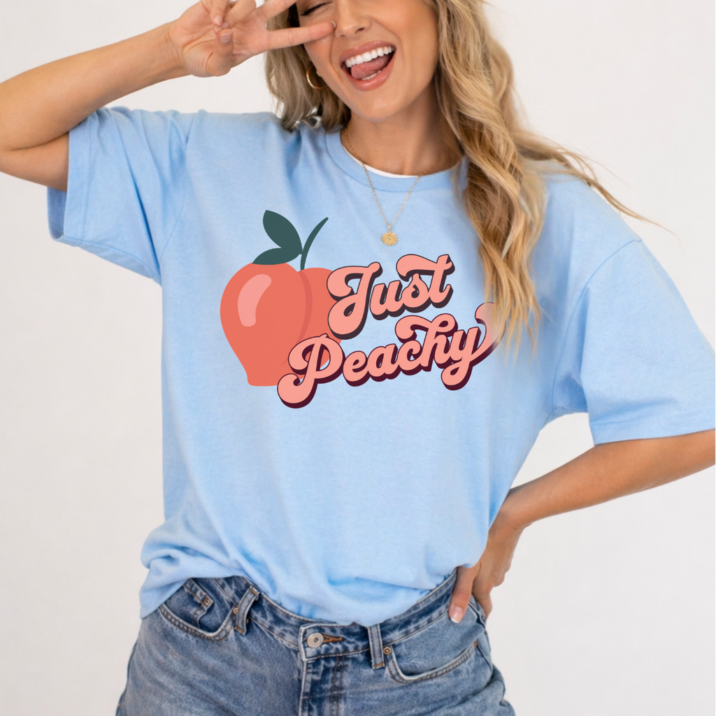 Person wearing a light blue t-shirt with 'Just Peachy' design on a plain background