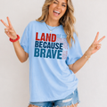 Woman wearing a light blue t-shirt with patriotic text, making peace signs.