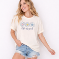 Woman wearing a 'life is good' t-shirt with floral designs on a white background