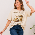 Woman wearing a beige t-shirt with 'Mama Makes the Dough' graphic design.