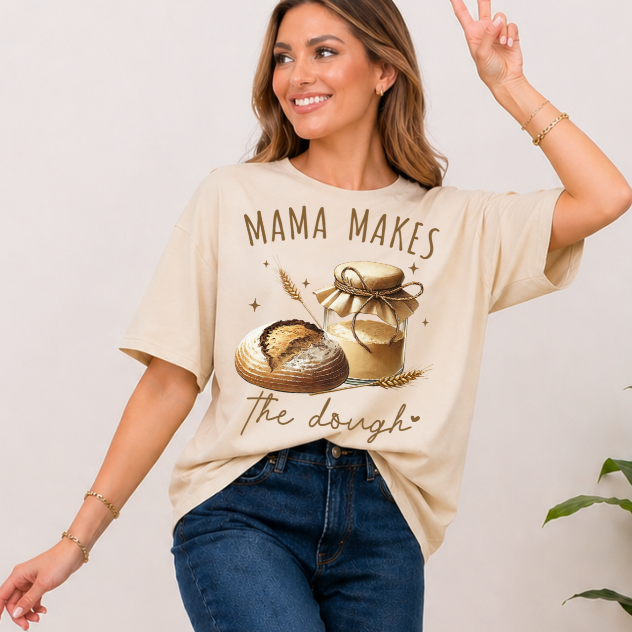 Woman wearing a beige t-shirt with 'Mama Makes the Dough' graphic design.