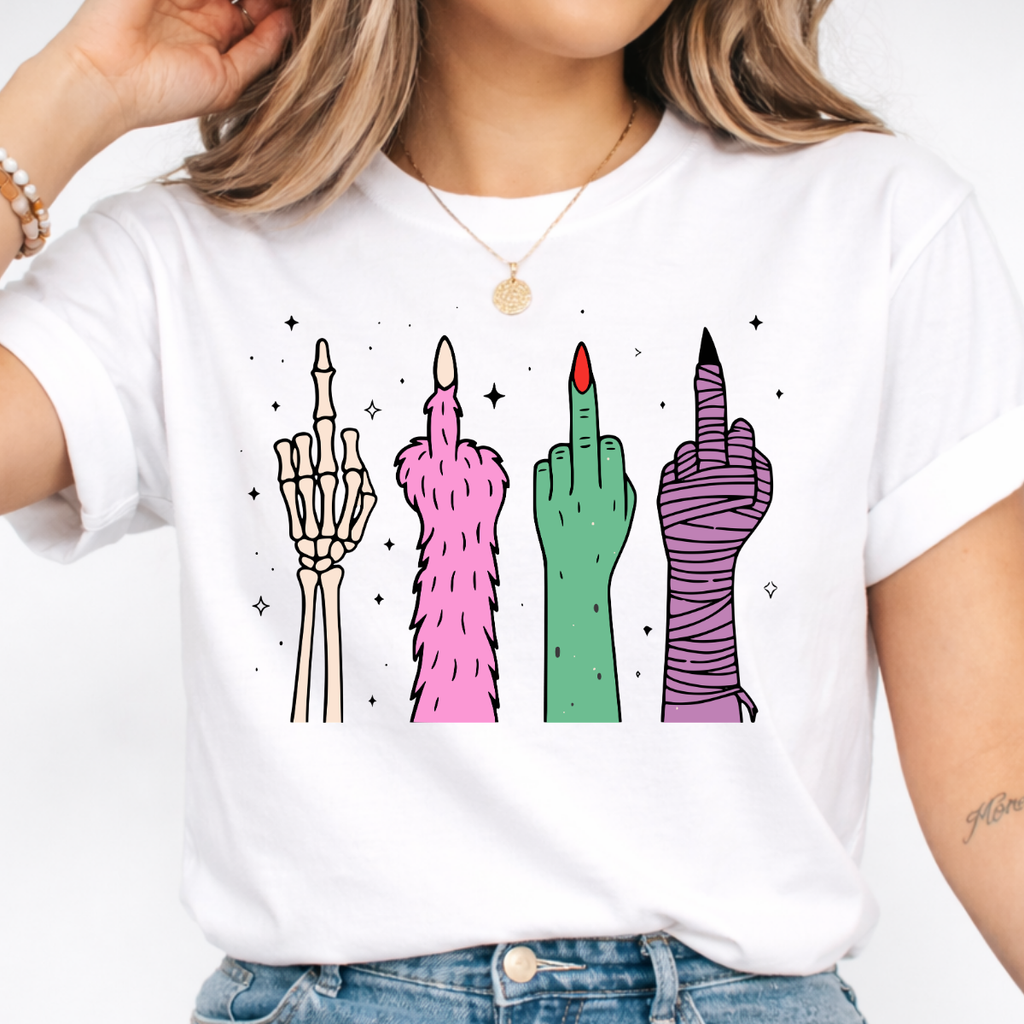 Woman wearing a white Halloween graphic tee with colorful skeleton, monster, witch, and mummy middle finger hands.