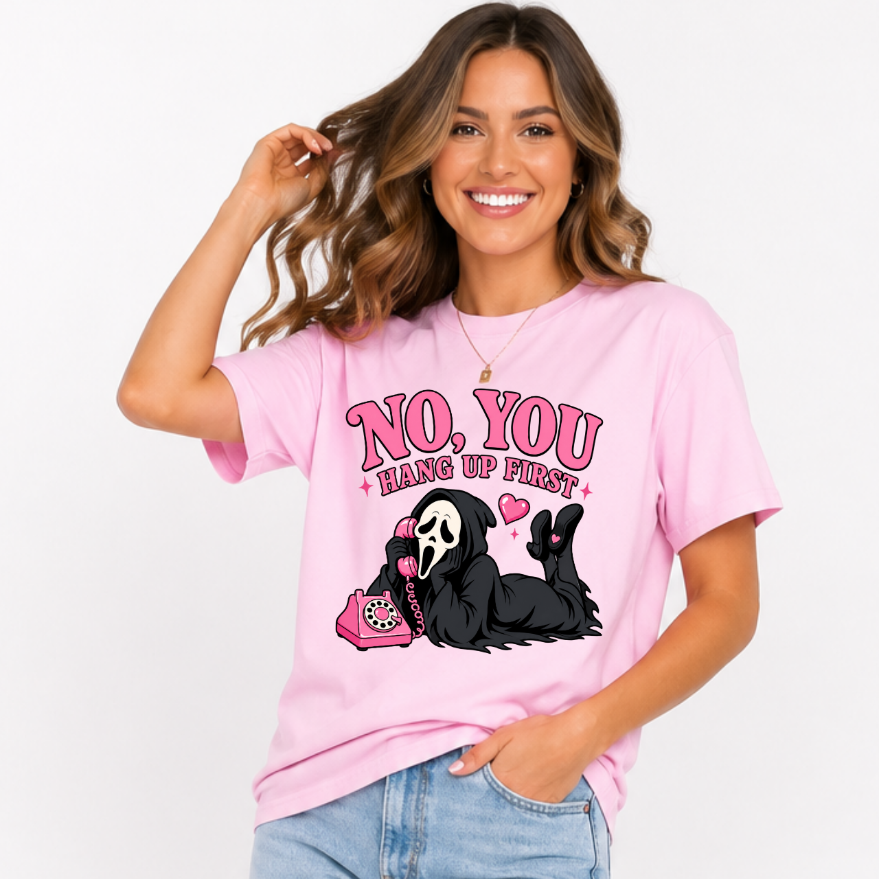 Woman wearing a light pink No You Hang Up First Halloween graphic tee with a masked horror character and pink telephone.