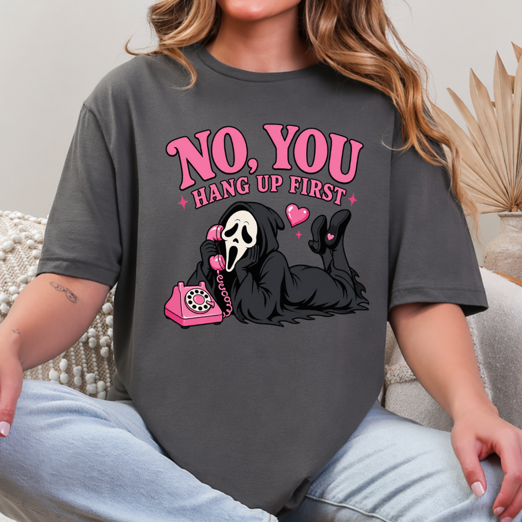 Woman wearing a charcoal No You Hang Up First Halloween graphic tee with a masked horror character and pink telephone.