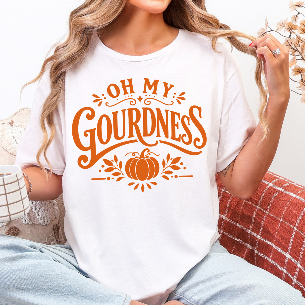 Woman wearing a white Oh My Gourdness fall graphic tee with orange lettering and a pumpkin design.