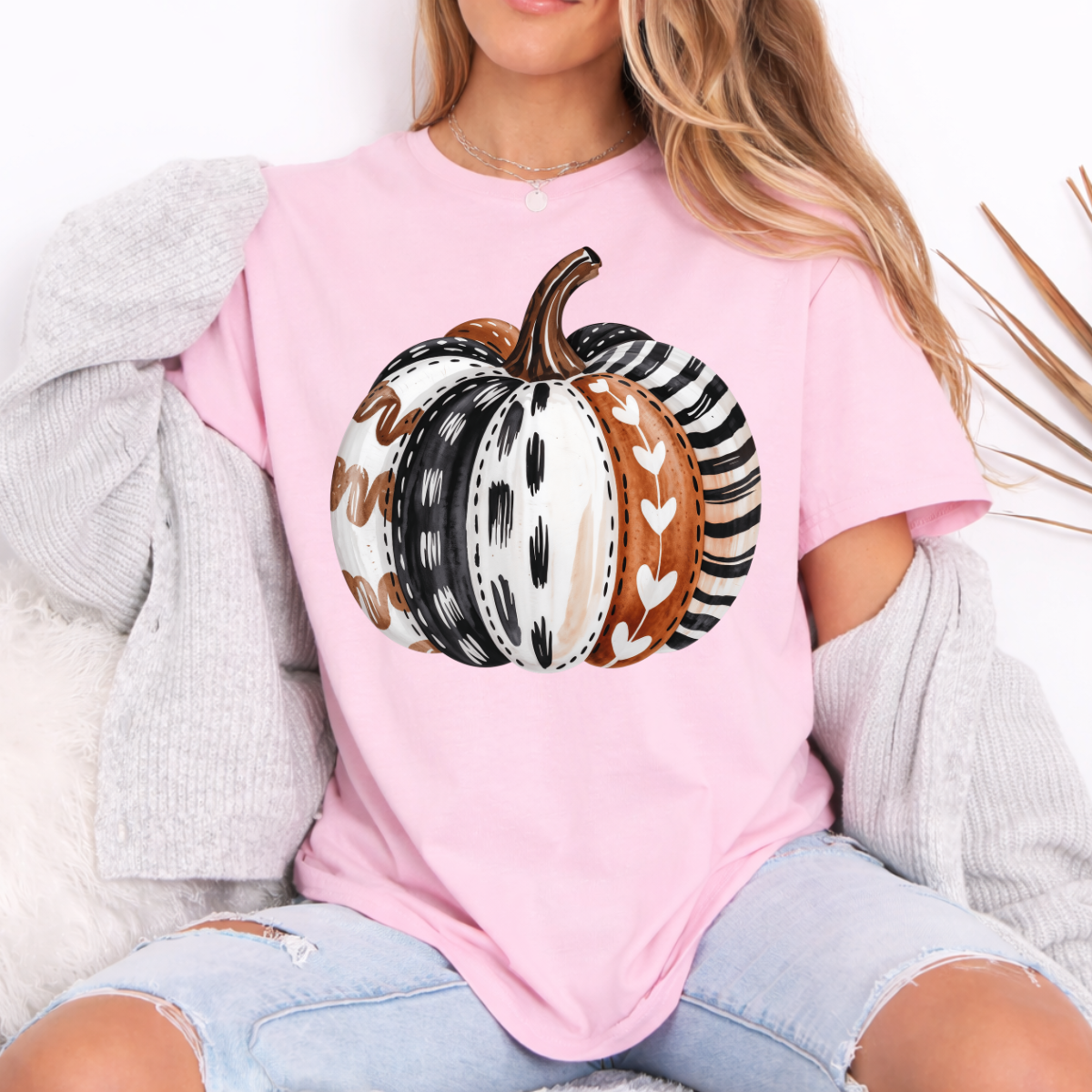 Woman wearing a light pink patterned pumpkin fall graphic tee with a neutral boho pumpkin design.
