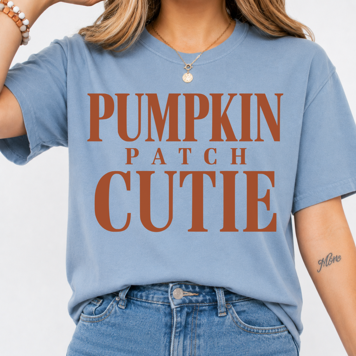 Woman wearing a stone blue Pumpkin Patch Cutie fall graphic tee with rust orange lettering.