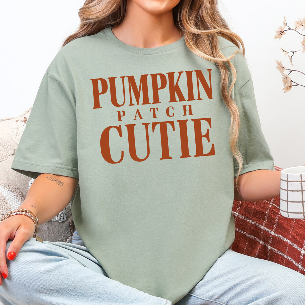 Woman wearing a sage green Pumpkin Patch Cutie fall graphic tee with rust orange lettering.