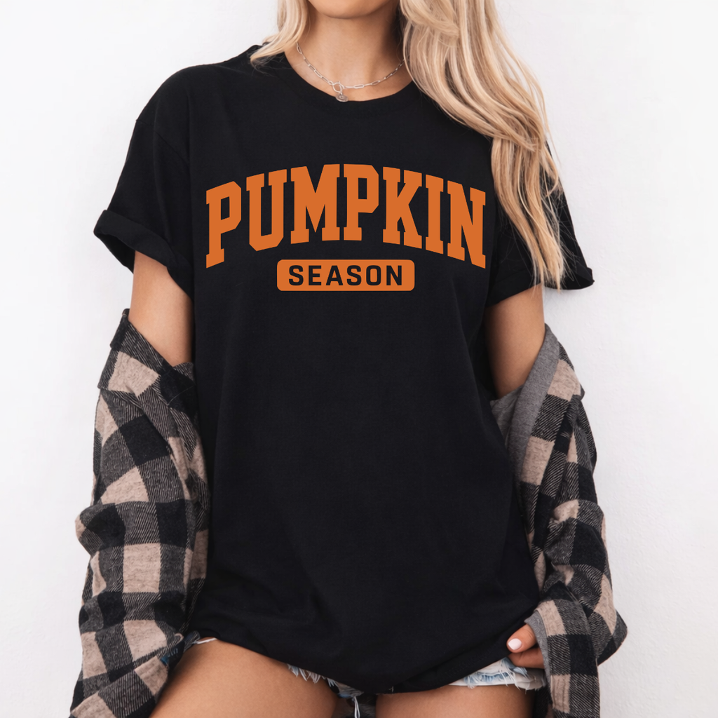 Woman wearing a black Pumpkin Season fall graphic tee with bold orange collegiate lettering.