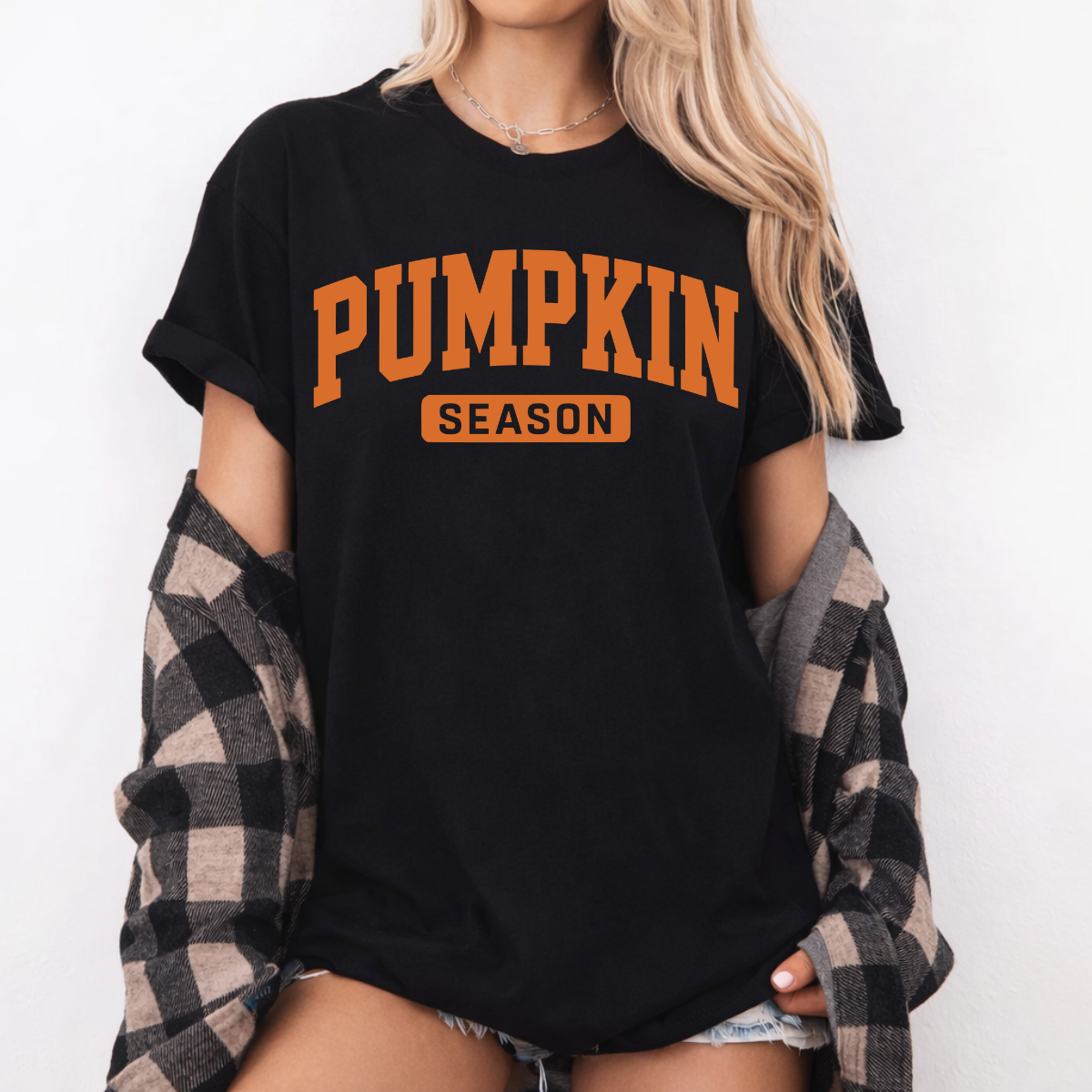Woman wearing a black Pumpkin Season fall graphic tee with bold orange collegiate lettering.