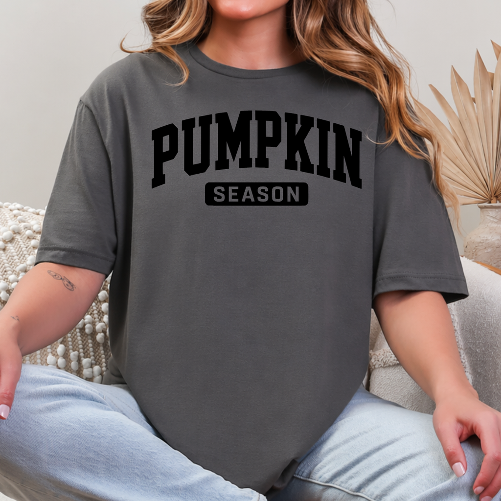 Woman wearing a charcoal Pumpkin Season fall graphic tee with bold black collegiate lettering.